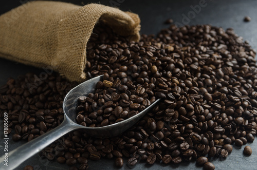Roasted coffee beans in burlap sack bag on old rusty background
