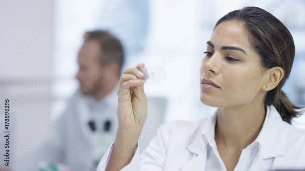 Close up medical researcher in the lab looking at a slide under microscope Close up medical researcher in the lab looking at a slide under microscope