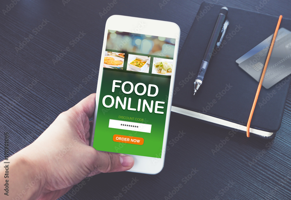 Hand holding mobile phone and order food online for app with promo code with credit card on notebook on black wood table background,Digital marketing concept ,office desk