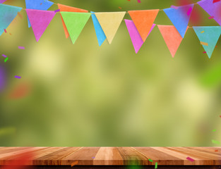 Colorful flag banner and confetti on wood table with blur green tree bokeh background, Template mock up for montage of product.party garland holiday backdrop for display design.