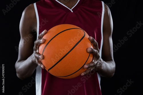 Mid section of player holding basketball