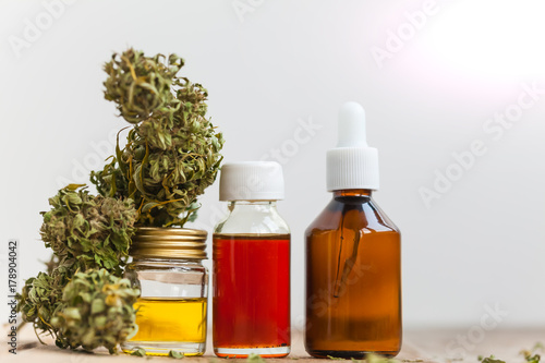 Fototapeta Naklejka Na Ścianę i Meble -  alternative medicine green leaves of medicinal cannabis with extract oil on a wooden table