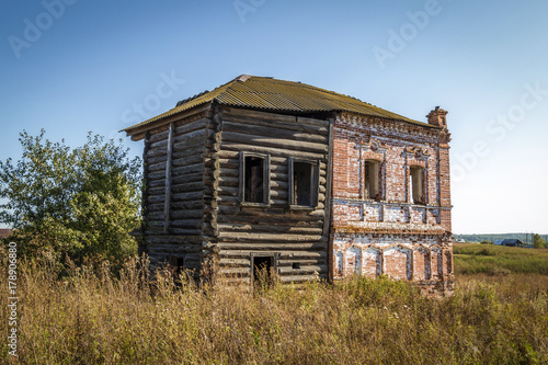 The old abandoned historic building of red brick and logs.