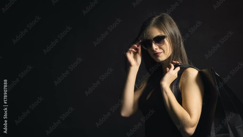 Portrait of beautiful caucasian girl, in cool sunglasses and sexy black dress, on black friday in the black background Portrait of beautiful caucasian girl, in cool sunglasses and sexy black dress, on black friday in the black background