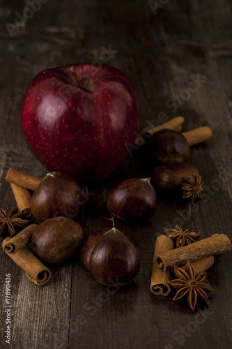 Chestnuts and Apple  together cinnamon and star anise on a wooden background