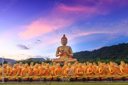 Big golden buddha statue and many small golden buddha statues sitting in row at at Buddha Memorial park, Nakornnayok Thailand. photo