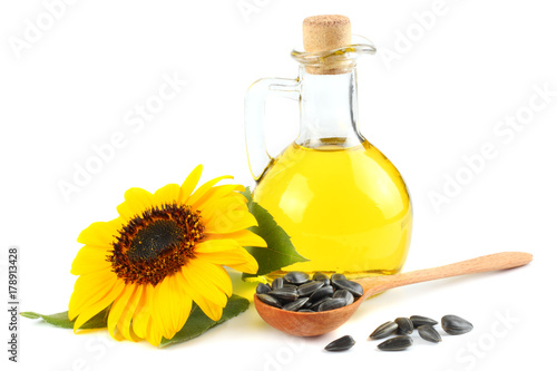 Sunflower oil in glass jug, seeds and flower isolated on white background photo