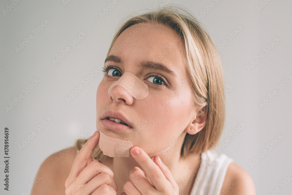 Face of woman looking at camera applying the plaster under her eye during makeup procedure, isolated on white background. Horizontal view. Face of woman looking at camera applying the plaster under her eye during makeup procedure, isolated on white background. Horizontal view.