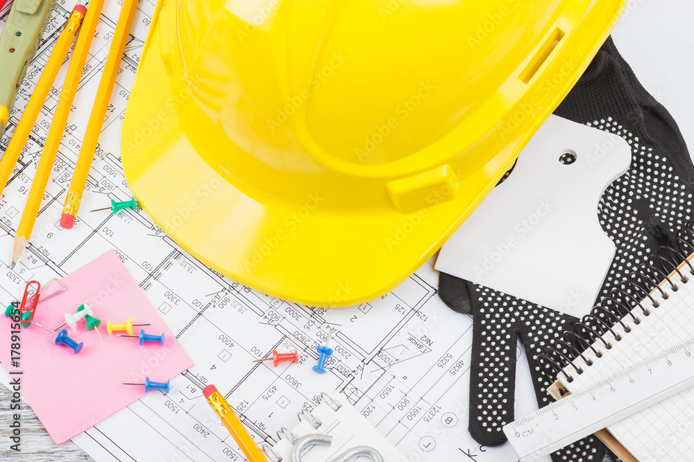 Drawings, yellow helmet and construction tools, wooden background Drawings, yellow helmet and construction tools, wooden background