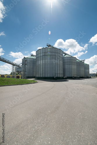 High metal silos for storage of wheat and barley. Sunny day, the blue sky.