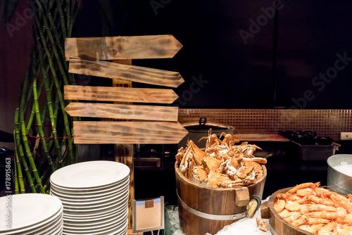 Steamed crabs and prawns on ice in wooden buckets with directional sign for menu