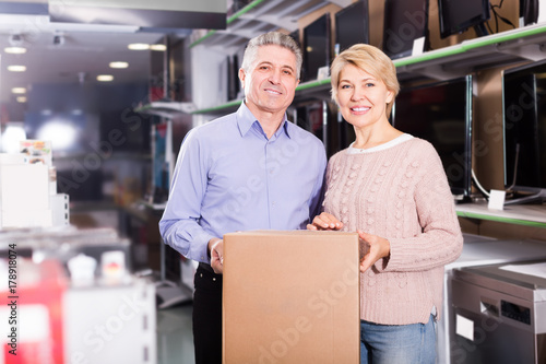 mature married couple in shop packed household appliances into boxes