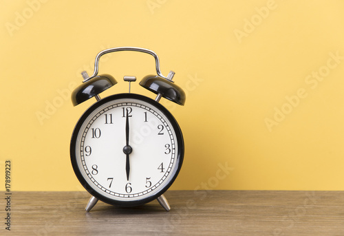alarm clock on wood table with yellow background and copy space for product display montage.