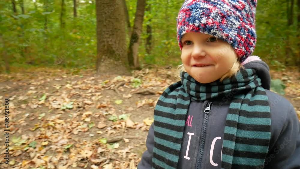 Autumn portrait of a girl in a hat and scarf. The child walks in the forest. Autumn portrait of a girl in a hat and scarf. The child walks in the forest.