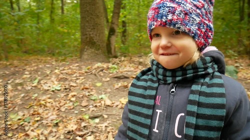 Autumn portrait of a girl in a hat and scarf. The child walks in the forest. photo