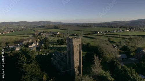 Orbiting aerial view of an English church surrounded in green countryside. photo