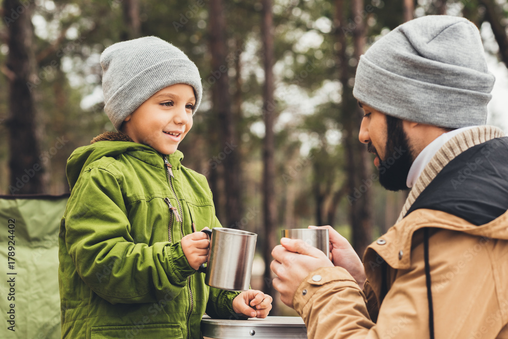 father and son with cups of tea outdoors - obrazy, fototapety, plakaty 
