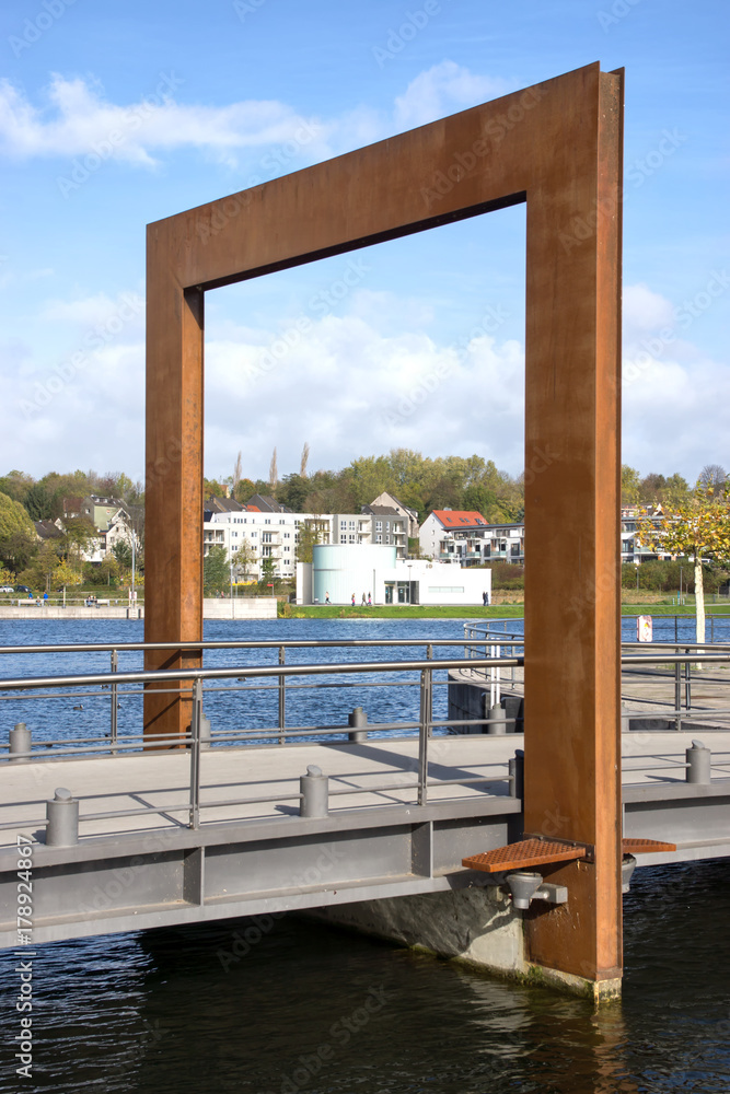 Fototapeta premium Stahlskulptur an der Brücke zur Phönixinsel am Phönixsee in Dortmund, Nordrhein-Westfalen