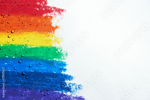 There are drops of water dripping over a rainbow with crayons.
