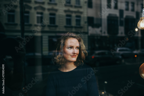 Junge blonde Frau schaut lächelnd aus dem Fenster © kay fochtmann