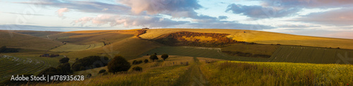 An English countryside panorama at sunset centred around a fenced opening.