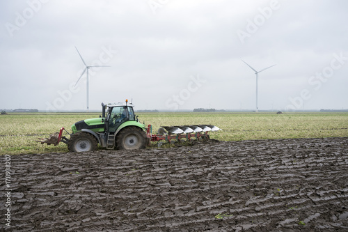 freshly plowed land and tractor with plough in dutch field end of autumn in the neth photo