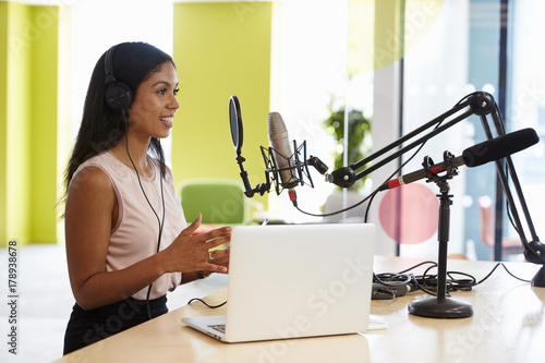 Young mixed race woman recording a podcast in a studio photo