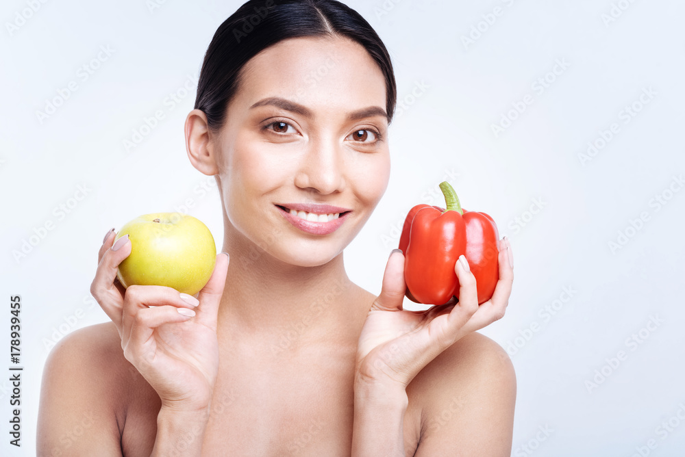 Smiling woman holding bell pepper and apple