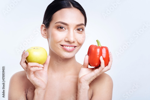 Smiling woman holding bell pepper and apple
