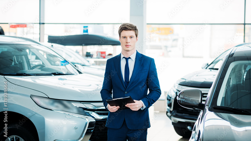 manager standing between cars in showroom