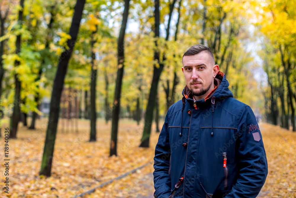 man  walks in the autumn park. portrait of a man look at the camera