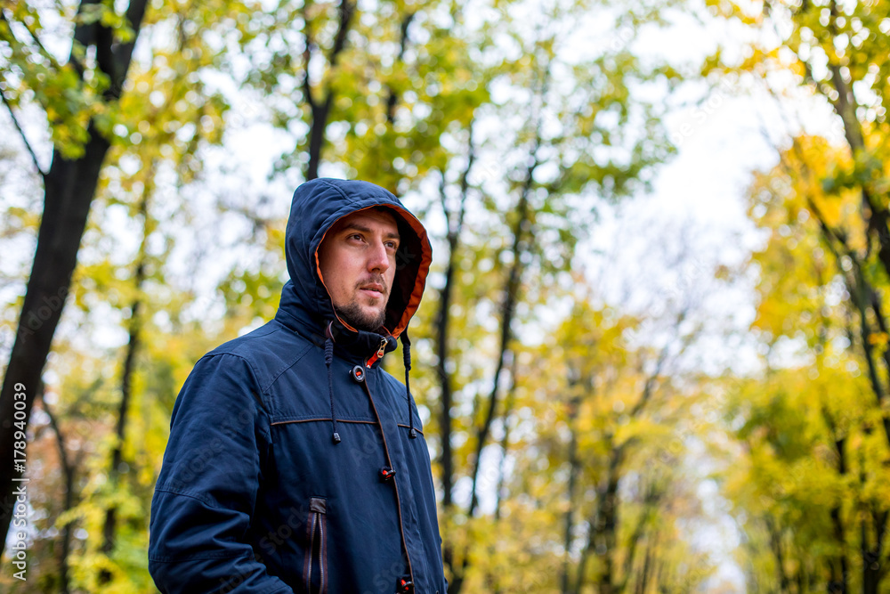 man walks in the autumn park. portrait of a man in a hood man walks in the autumn park. portrait of a man in a hood