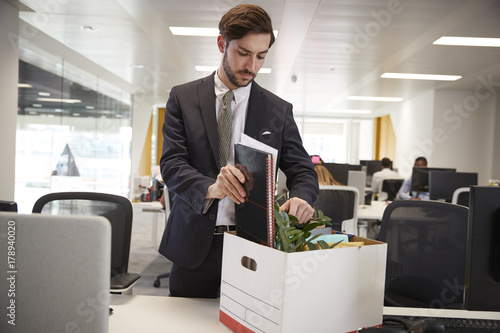 Fired male employee packing box of belongings in an office photo