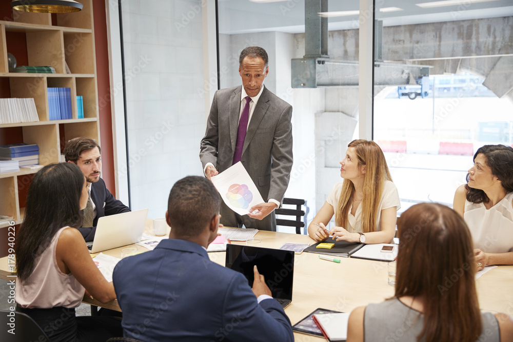 Male boss holding document at a business boardroom meeting Male boss holding document at a business boardroom meeting