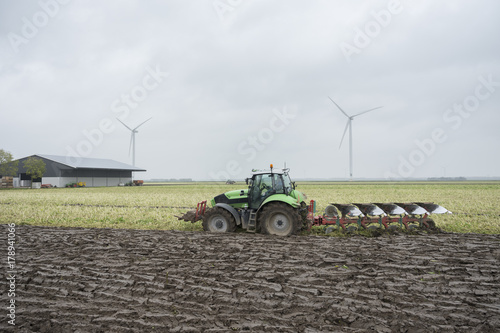 freshly plowed land and tractor with plough in dutch field end of autumn in the neth photo