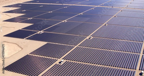 Aerial view flying over large industrial solar energy farm in desert 