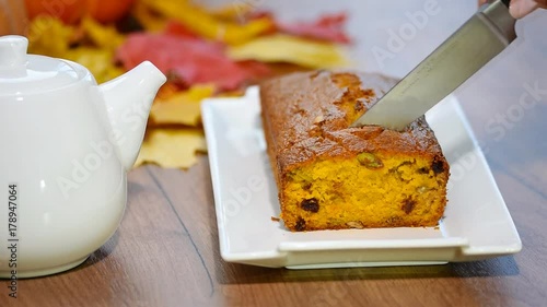 Female hand with a knife cuts the pumpkin bread photo