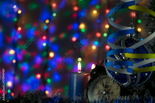 two candles with clock and Christmas toy with multi-colored lights on background
