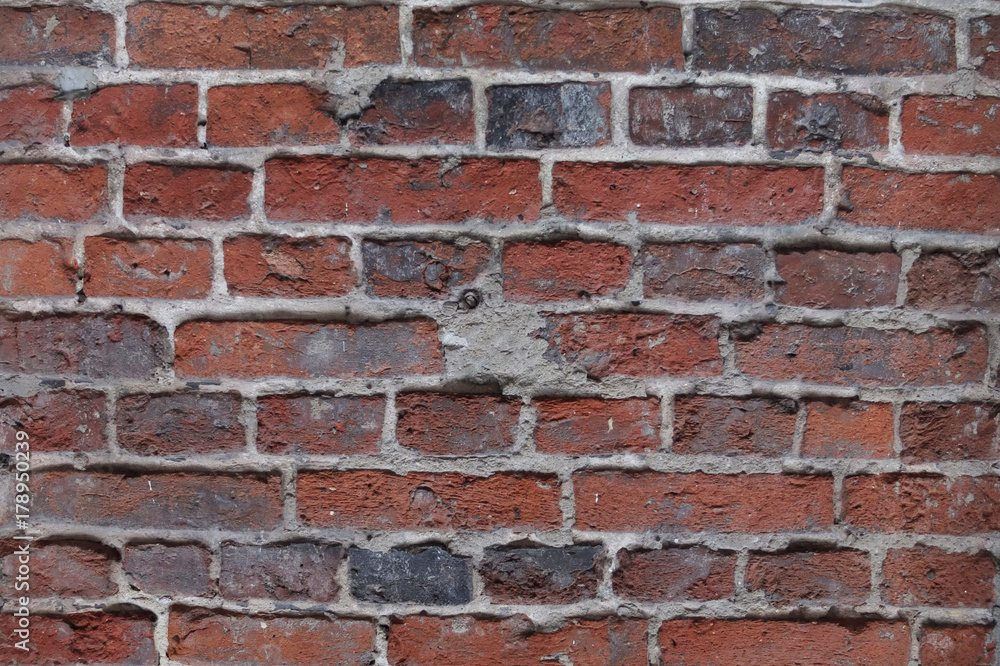 Fototapeta premium fragment of destroyed brick wall with convex welds of cement