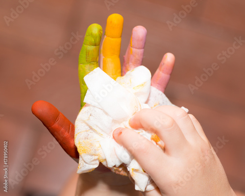 The baby wipes her hands with a napkin