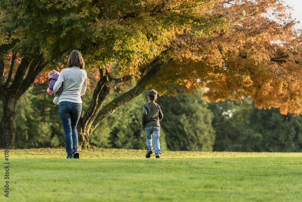 Mother holding baby next to her son in Autumn Mother holding baby next to her son in Autumn