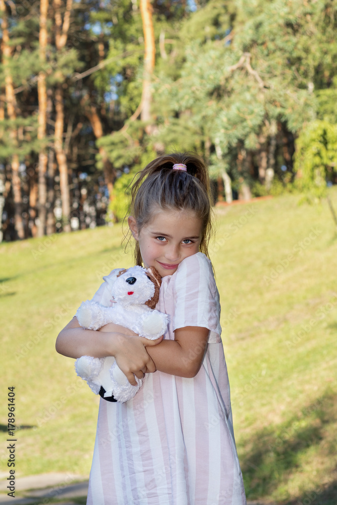 Cute little girl with a favorite toy in the city park on a sunny summer day Cute little girl with a favorite toy in the city park on a sunny summer day
