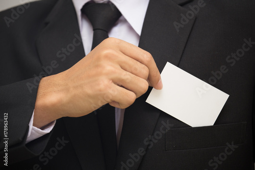 Man holding white business card on concrete wall background
