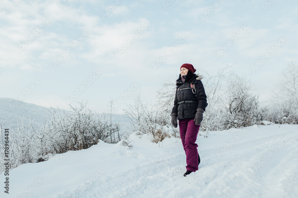 Smiling woman dressed warm enjoying a walk in snowy country