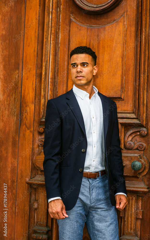 African American Businessman working in New York. Wearing black blazer, white  shirt, gray pants, a college student standing by vintage office doorway,  looking up, thinking. Instagram filtered effect. Photos | Adobe Stock