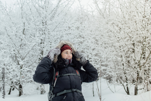 Smiling woman dressed warm walking through forest in winter