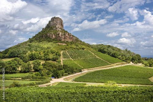France; Solutre-Pouilly: Panoramic view with Rock of Solutre, green vineyards, trees and cloudy blue sky - scenery photo