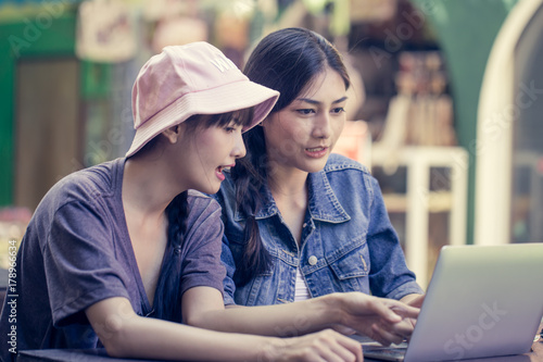 Portrait of Happy traveler Woman in city. Asian women using Laptop for seach location, People with Traveler Concept. Vintage Tone.