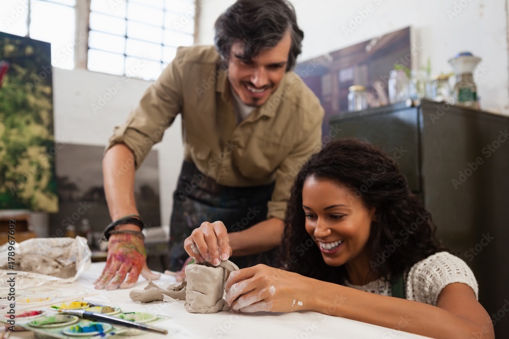 Man assisting woman in molding clay Man assisting woman in molding clay