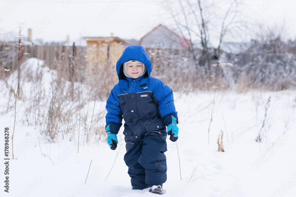Happy boy walking in a snow - winter leisure for children